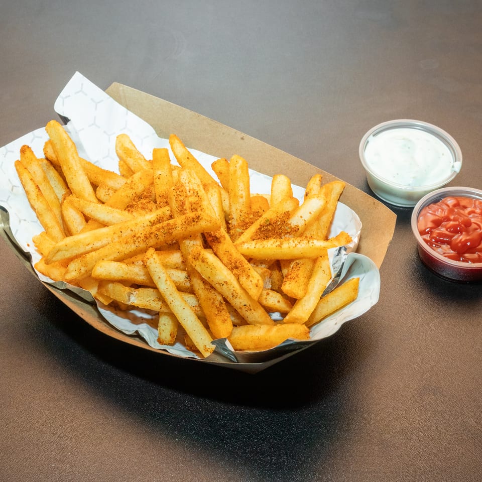 Seasoned golden French fries served in a paper-lined basket with ranch and ketchup dipping sauces.